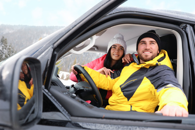 Photo of Happy couple in car outdoors. Winter vacation