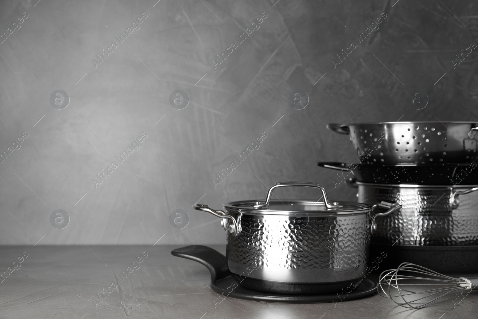 Photo of Set of clean cookware on table against grey background. Space for text