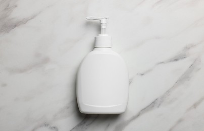 Photo of Dispenser of liquid soap on white marble table, top view