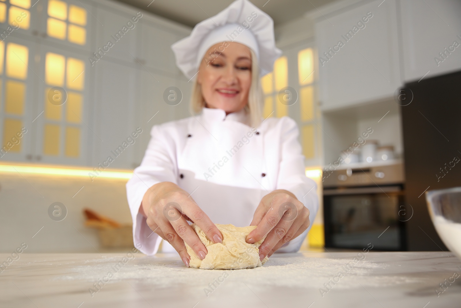 Photo of Professional chef cooking dough at table in kitchen, focus on hands