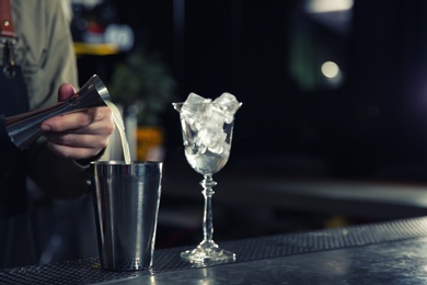 Photo of Barman pouring lemon juice for cosmopolitan martini cocktail into shaker at counter, closeup. Space for text