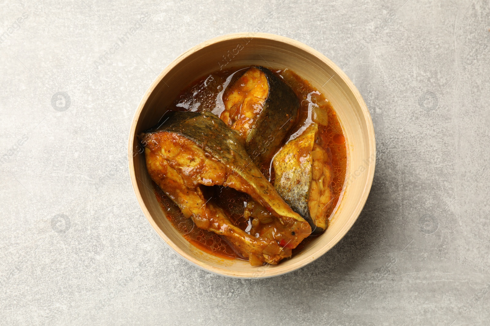 Photo of Tasty fish curry on light grey table, top view. Indian cuisine