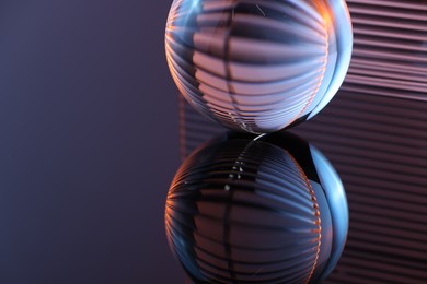 Photo of Transparent glass ball on mirror surface, closeup