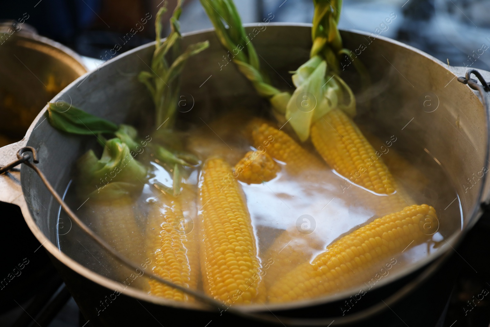 Photo of Delicious fresh corn cobs in pot with hot water, closeup