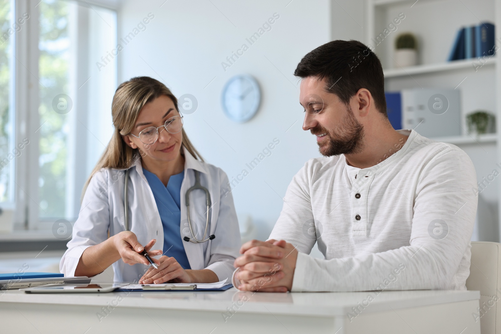 Photo of Professional doctor working with patient at white table in hospital