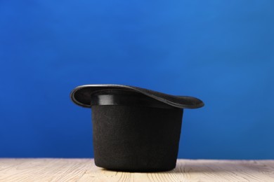 Photo of Magician's hat on wooden table against blue background