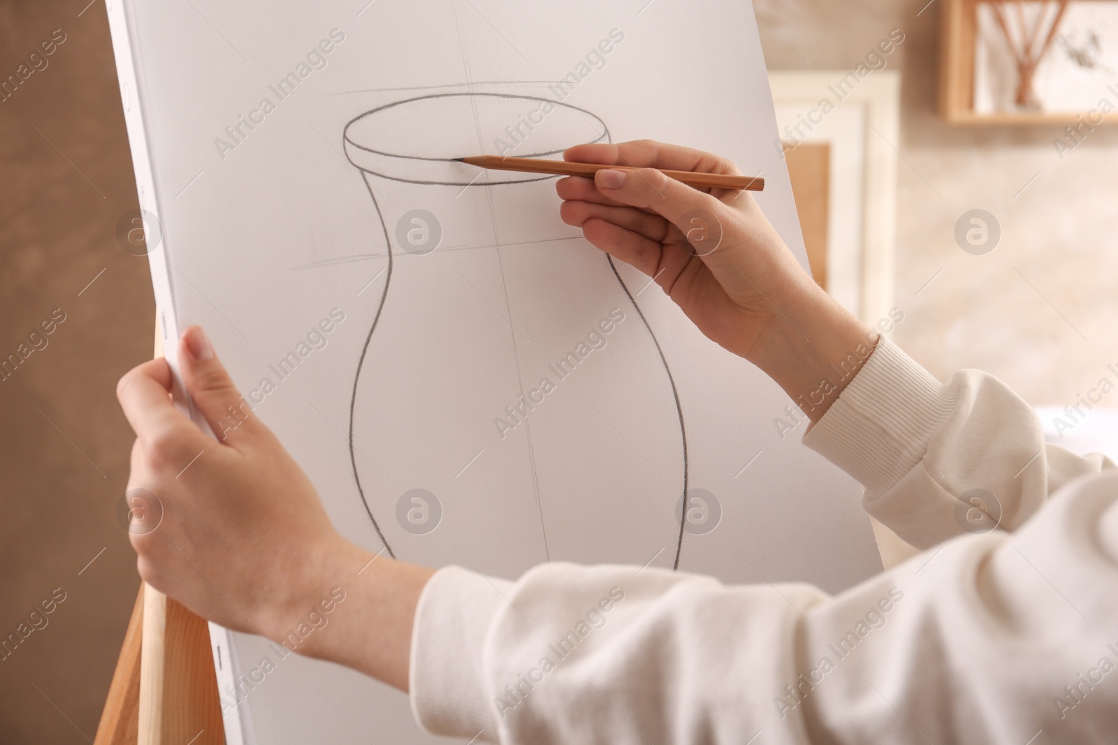 Photo of Woman drawing vase with graphite pencil on canvas indoors, closeup