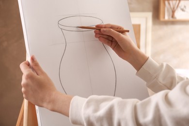 Woman drawing vase with graphite pencil on canvas indoors, closeup