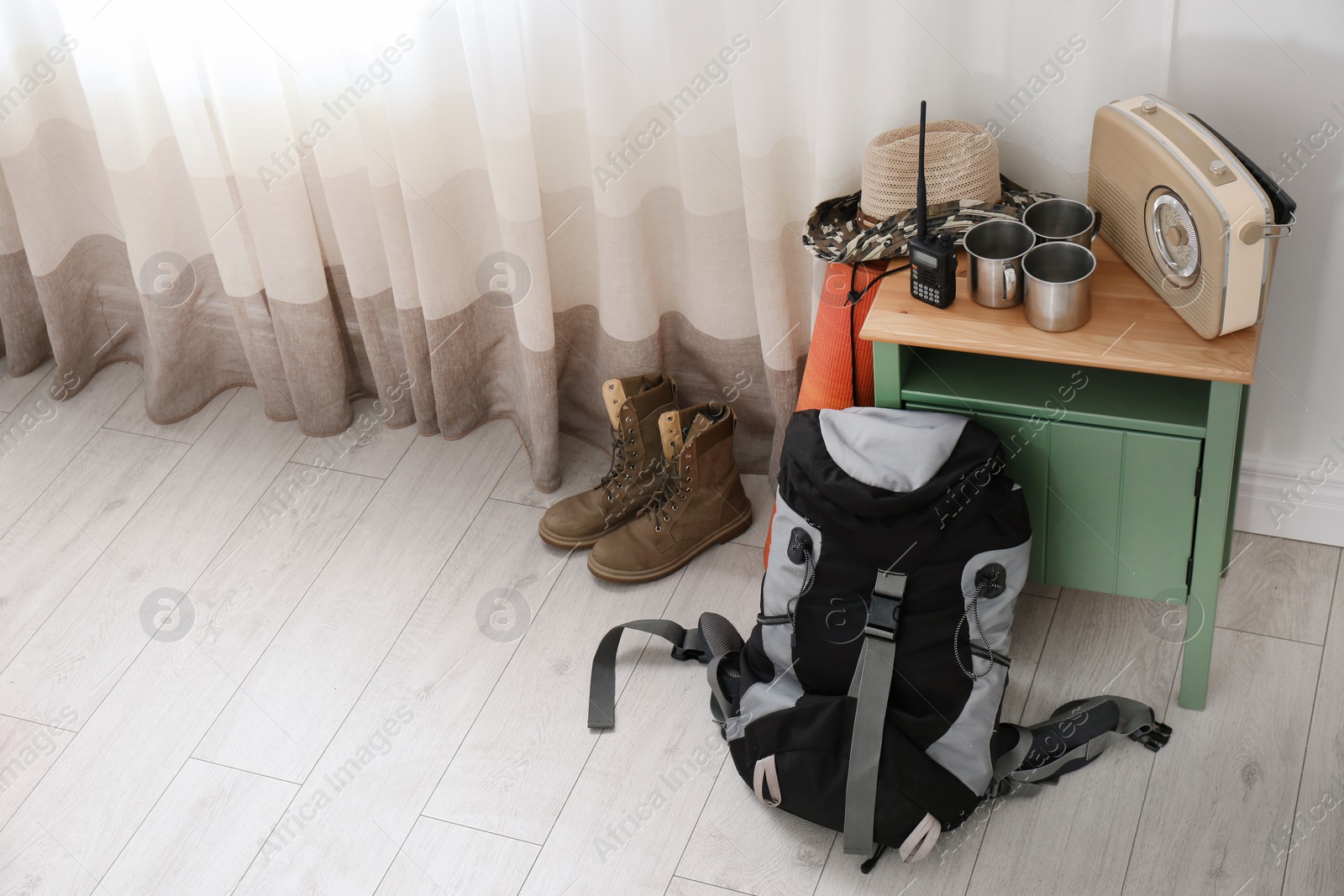 Photo of Set of camping equipment on floor near window. Space for text