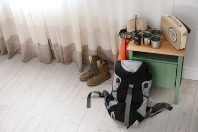 Set of camping equipment on floor near window. Space for text