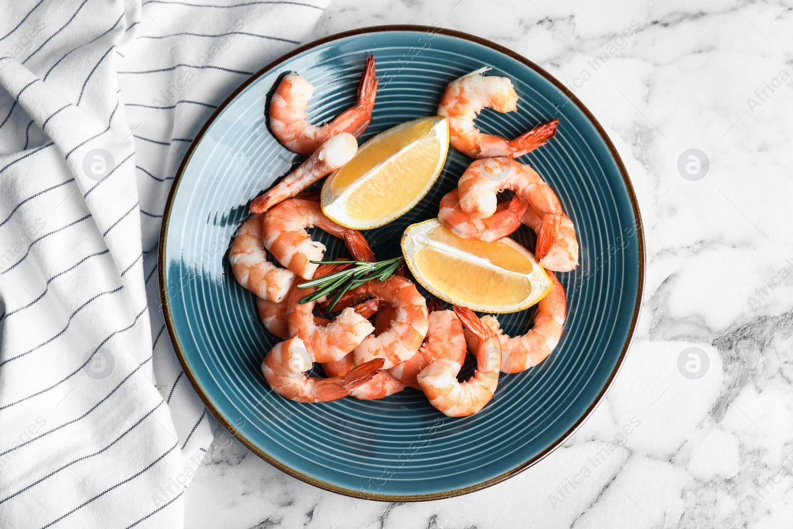 Photo of Delicious cooked shrimps with rosemary and lemon on white marble table, top view