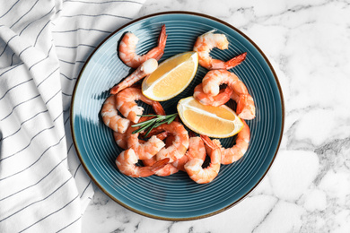 Photo of Delicious cooked shrimps with rosemary and lemon on white marble table, top view