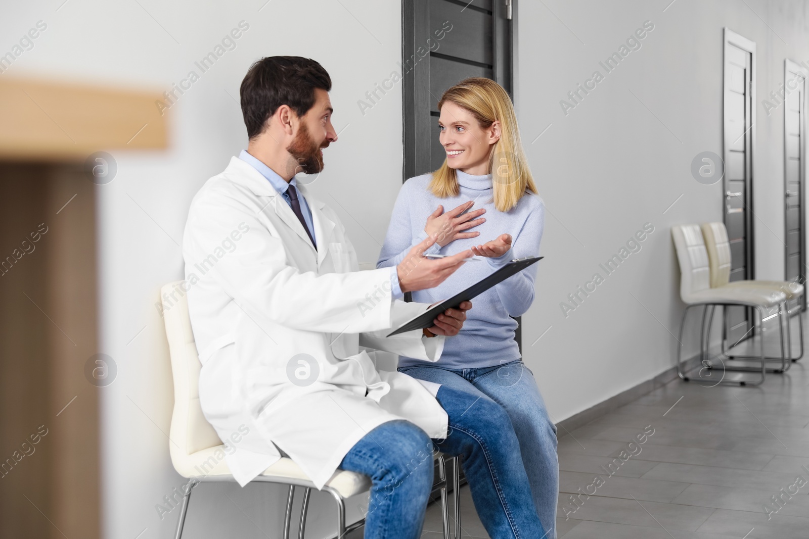 Photo of Doctor with clipboard consulting patient in clinic