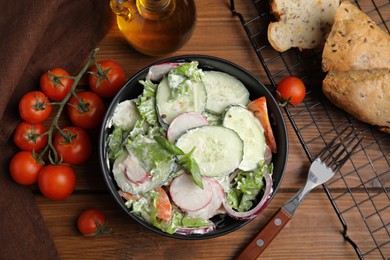 Photo of Bowl of delicious vegetable salad dressed with mayonnaise and ingredients on wooden table, flat lay