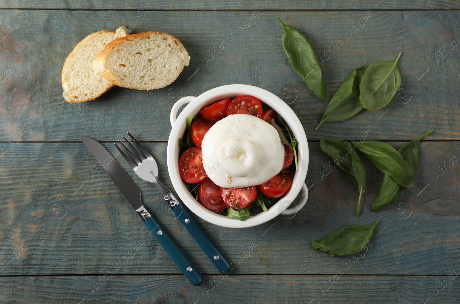 Photo of Delicious burrata cheese with tomatoes and basil served on grey wooden table, flat lay