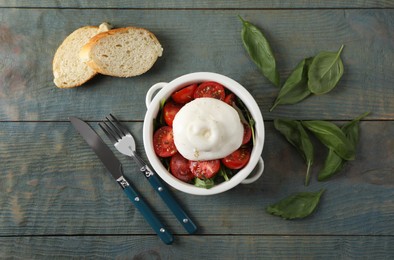 Photo of Delicious burrata cheese with tomatoes and basil served on grey wooden table, flat lay