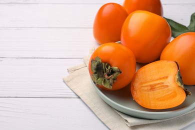 Delicious ripe juicy persimmons on white wooden table, space for text