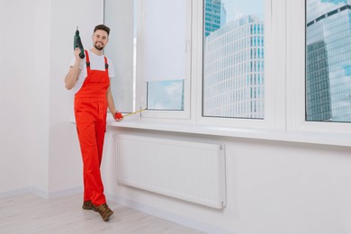 Photo of Worker holding tools for installation roller window blinds indoors