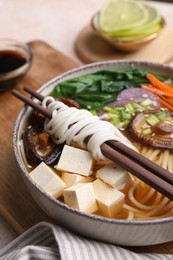 Photo of Bowl of vegetarian ramen and chopsticks on table, closeup