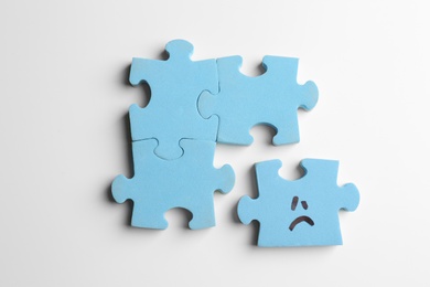 Puzzles with sad face on white background, flat lay