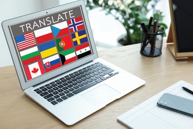 Image of Workplace with laptop and images of different flags on screen, phone, stationery in office