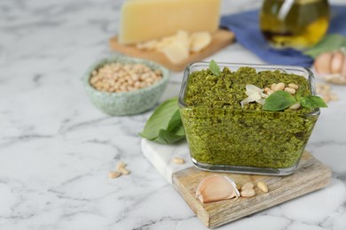 Photo of Delicious pesto sauce and ingredients on white marble table. Space for text