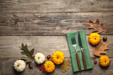 Cutlery, napkin and autumn decoration on wooden background, flat lay with space for text. Table setting