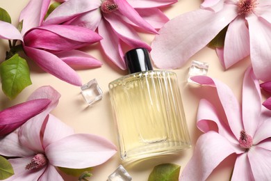 Photo of Beautiful pink magnolia flowers, bottle of perfume and ice cubes on beige background, above view