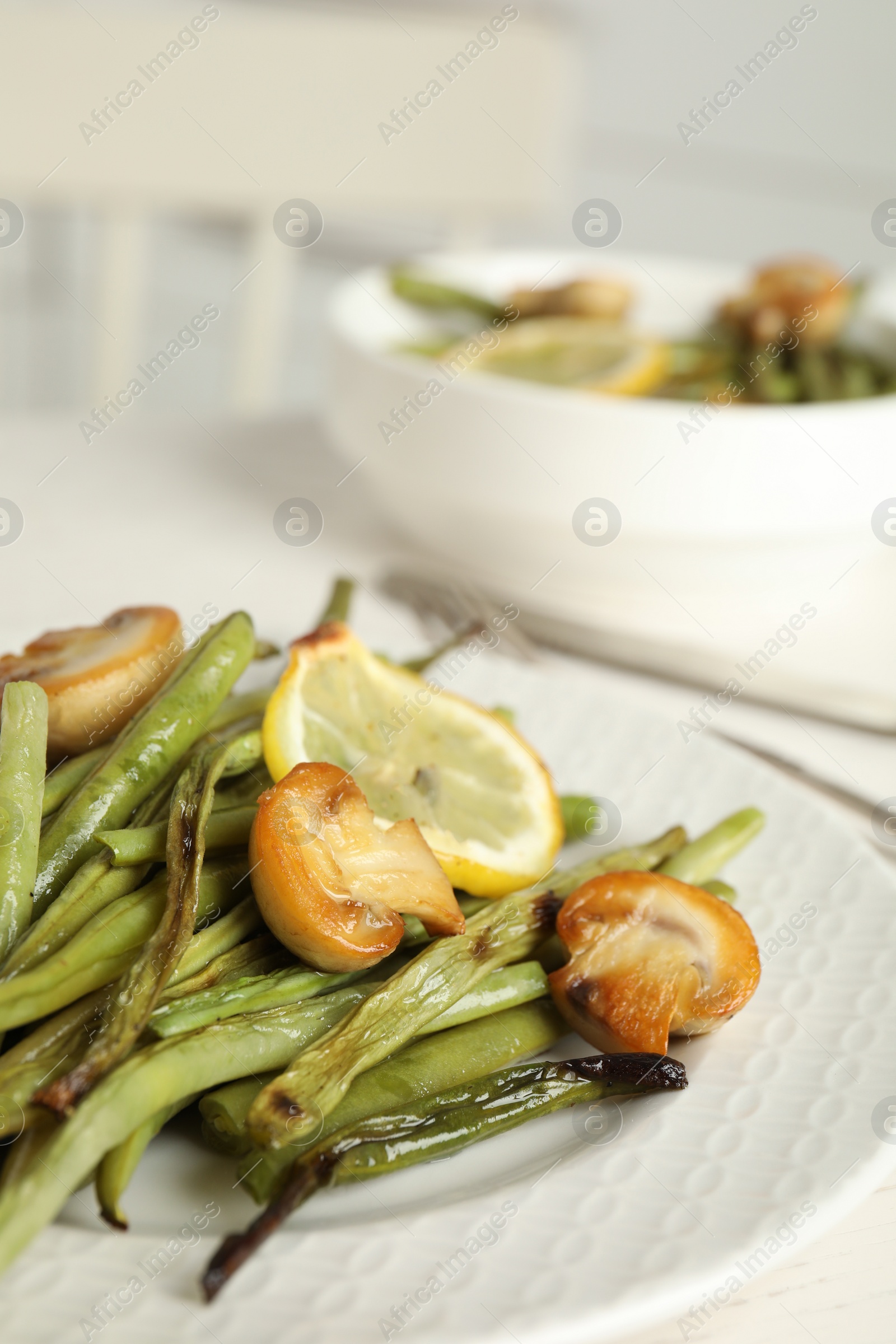 Photo of Delicious baked green beans with lemon and mushrooms on plate, closeup