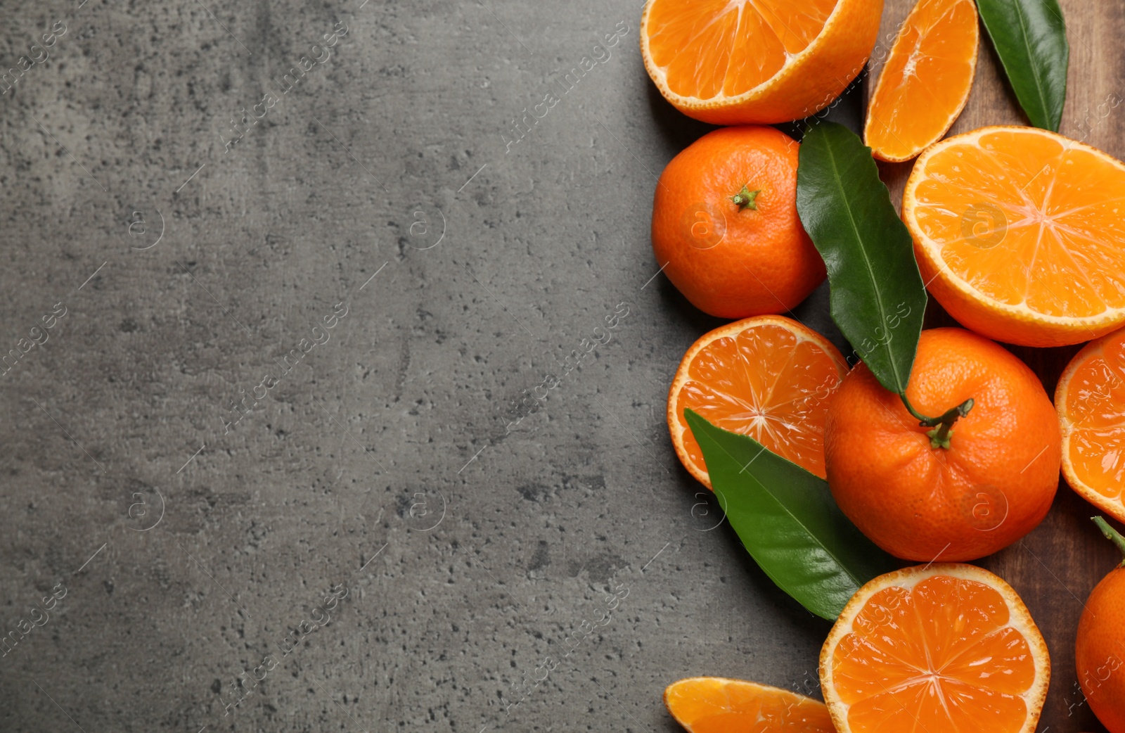 Photo of Fresh ripe tangerines and space for text on dark grey table, flat lay. Citrus fruit