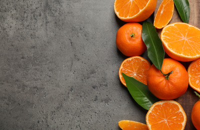 Photo of Fresh ripe tangerines and space for text on dark grey table, flat lay. Citrus fruit