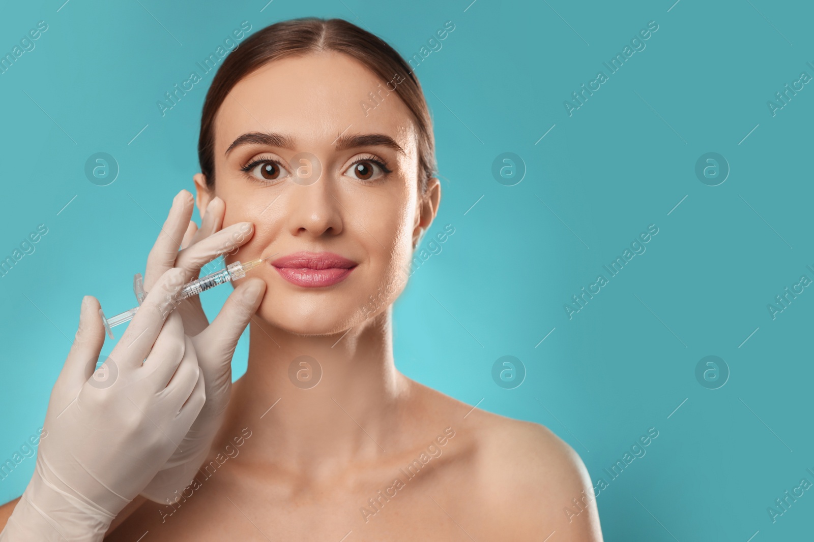 Photo of Beautiful woman getting facial injection on light blue background. Cosmetic surgery