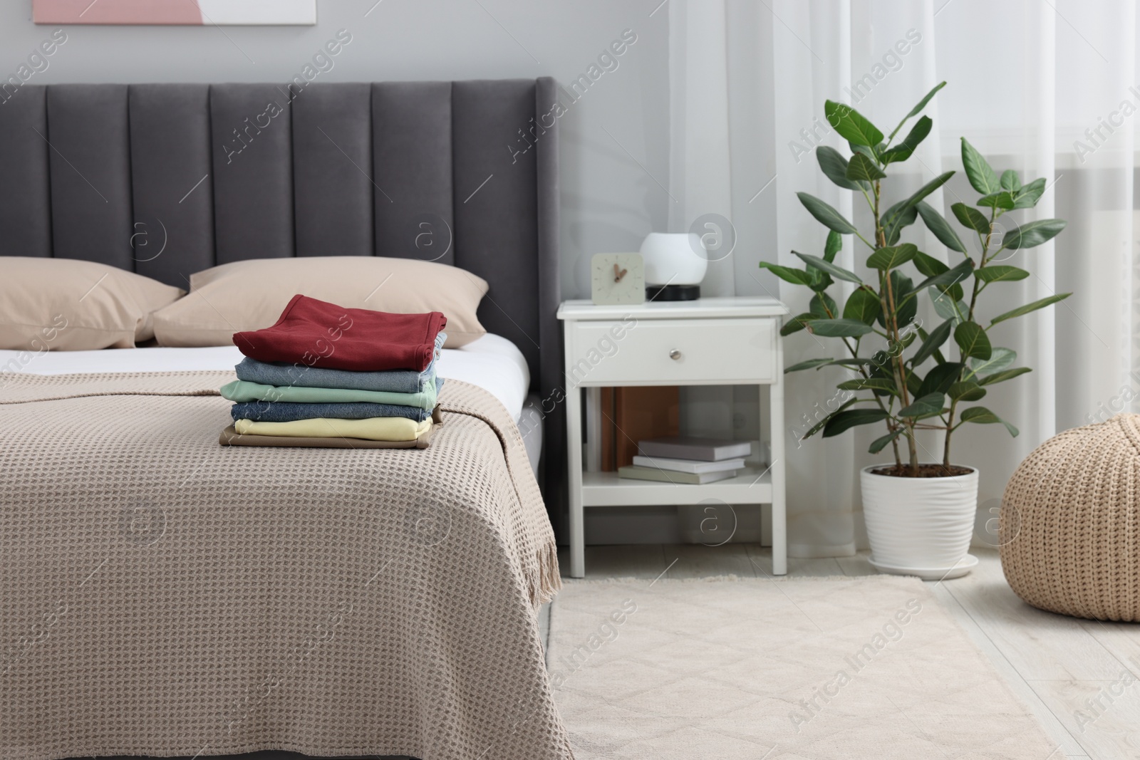 Photo of Stack of different folded clothes on bed at home