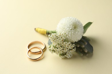 Photo of Small stylish boutonniere and rings on beige background