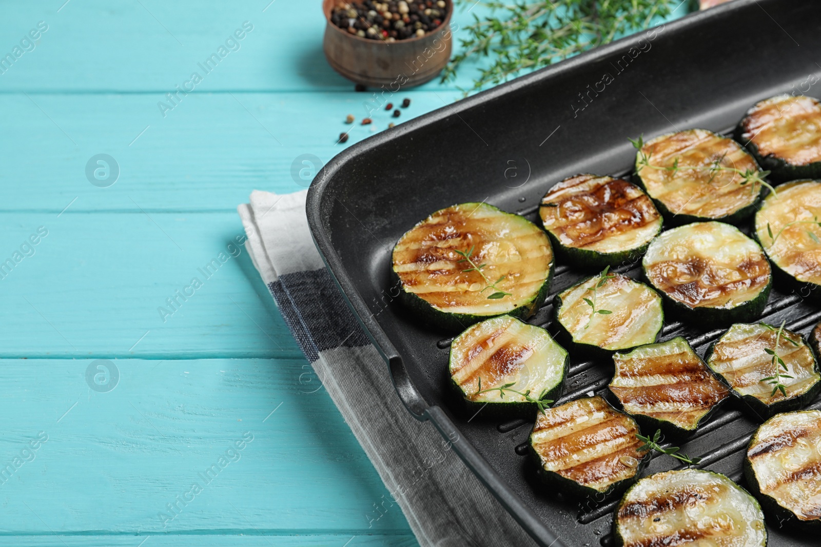 Photo of Grill pan of delicious zucchini slices on blue wooden table, closeup. Space for text