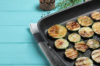 Photo of Grill pan of delicious zucchini slices on blue wooden table, closeup. Space for text