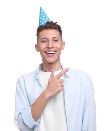 Happy young man in party hat pointing at something on white background