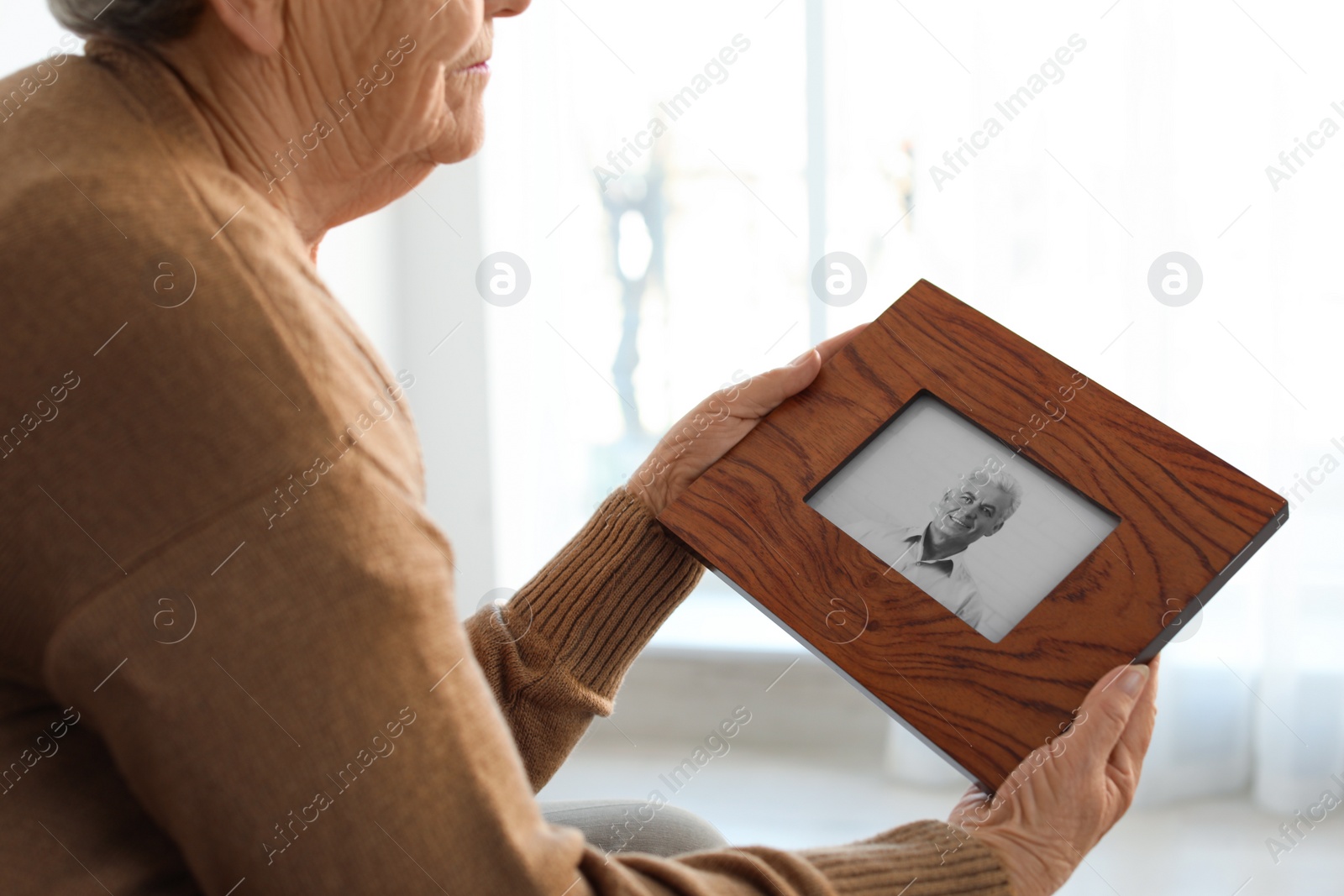 Photo of Elderly woman with framed photo of her son at home