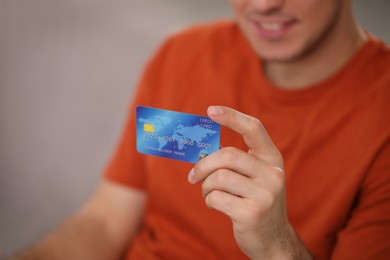 Photo of Man holding credit card for online payment indoors, closeup