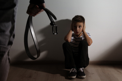 Photo of Man threatens his son with belt at home. Domestic violence concept