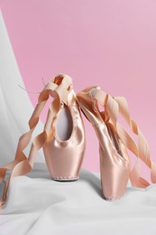 Photo of Ballet shoes. Stylish presentation of elegant pointes on pink background