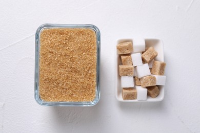 Photo of Different sugar cubes in bowls on white table, flat lay