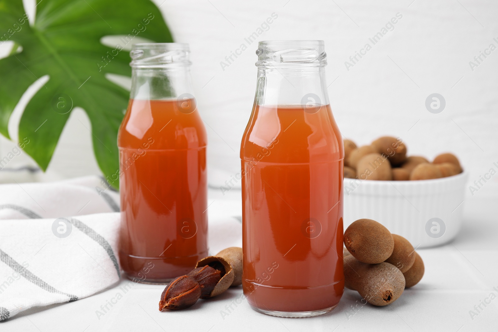 Photo of Tamarind juice and fresh fruits on white table