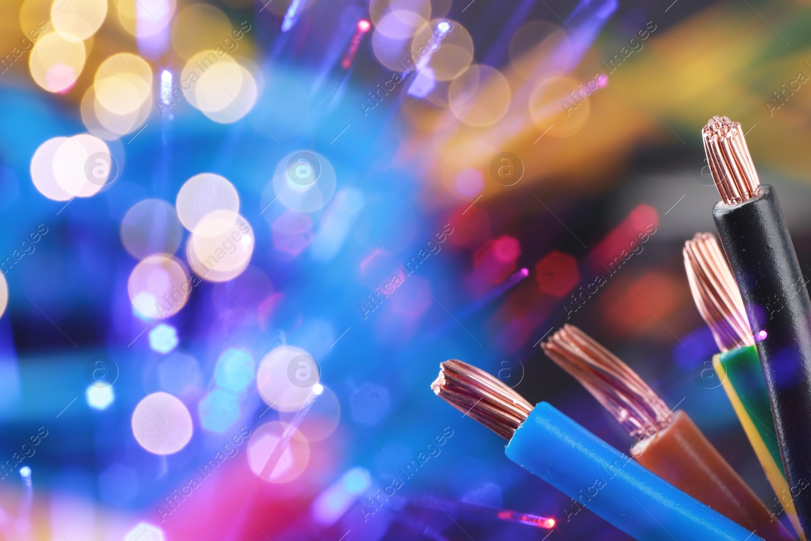 Image of Colorful electrical wires against color background with blurred lights, closeup. Space for text