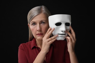 Multiple personality concept. Woman with mask on black background