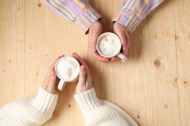 Photo of Women having coffee break at light wooden table, top view