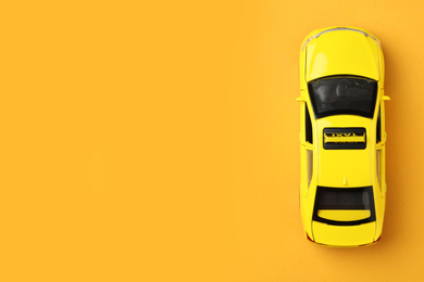 Photo of Yellow taxi car model on orange background, top view. Space for text