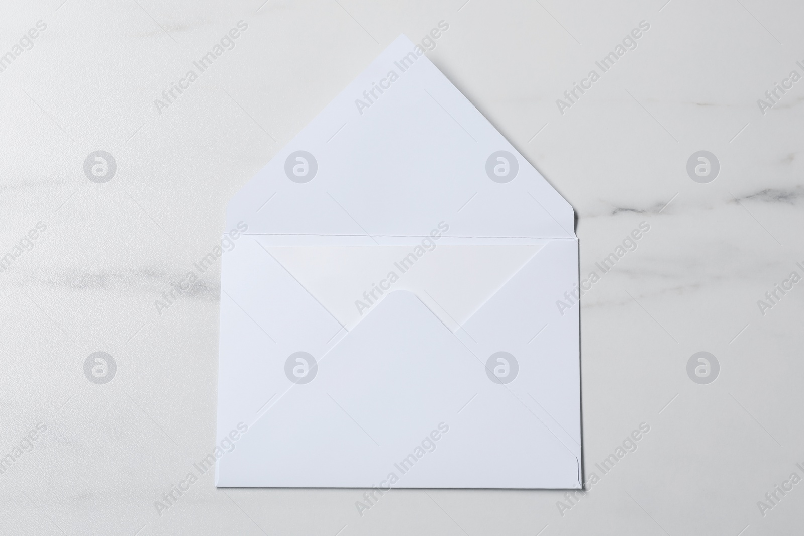 Photo of Letter envelope with card on white marble table, top view