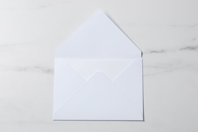 Letter envelope with card on white marble table, top view