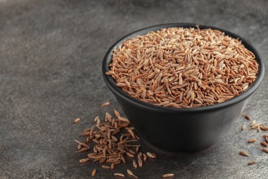 Photo of Bowl of caraway seeds on grey table, closeup. Space for text